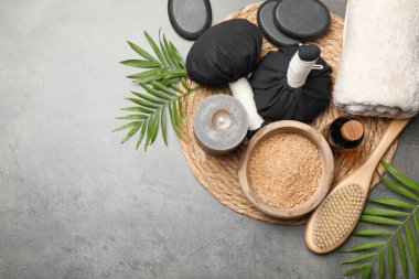 Bitkisel poşetlerle kaplıca kompozisyonu ve gri masada yanan bir mum. Metin için boşluk