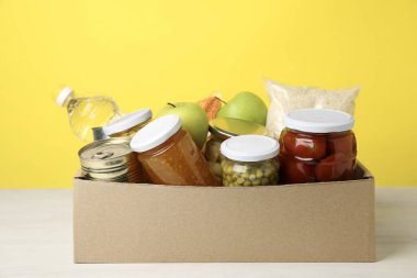 Sarı arka planda, kutuda bağışlanacak farklı gıda ürünleri.