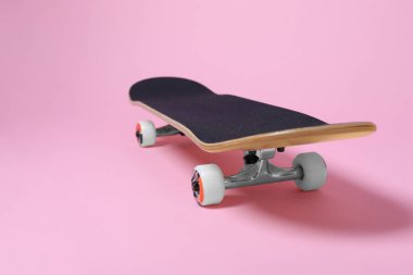 Pembe arka planda bir kaykay, yakın plan. Metin için boşluk