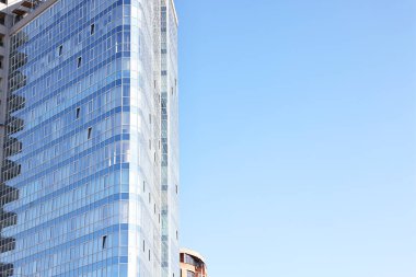 Mavi gökyüzüne karşı birçok penceresi olan modern binanın dış yüzeyi