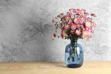 Ahşap masada güzel çiçekli vazo. Metin için boşluk