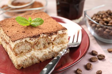 Lezzetli tiramisu tabağı, nane ve kahve çekirdekleri ahşap masada, yakın plan.