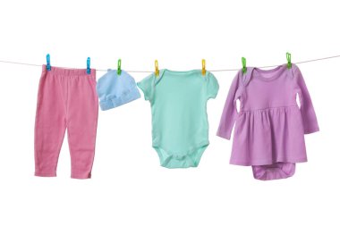 Different baby clothes drying on laundry line against white background