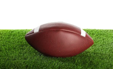 Beyazın üzerinde izole edilmiş yapay çimlerde Amerikan futbol topu. Spor malzemeleri.