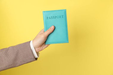Sarı arka planda pasaportu olan bir kadın, yakın plan. Metin için boşluk