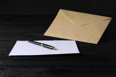Siyah ahşap masa üzerinde mektup ve kalemle Kraft kağıt zarfı. Tasarım için model
