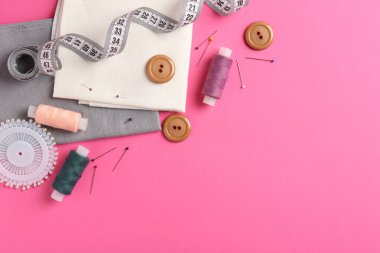 Pembe arka planda farklı dikiş malzemeleri var. Metin için boşluk