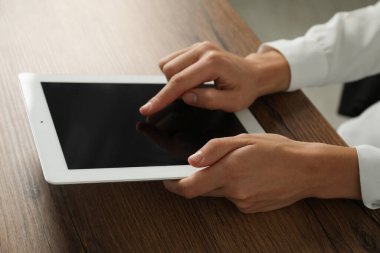 İş kadını, kapalı bir masada tablet kullanıyor, yakın plan. Modern teknoloji