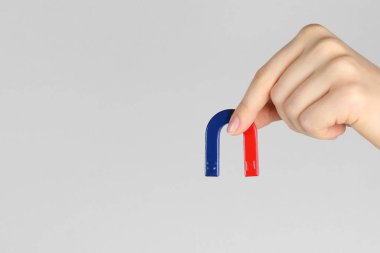 Gri arka planda at nalı mıknatısı olan kadın, yakın plan. Metin için boşluk