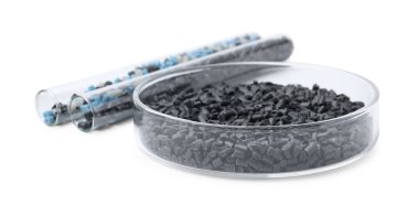Petri kabında renkli plastik granüller ve beyaz üzerinde izole edilmiş test tüpleri.