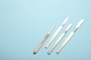 Açık mavi arka planda farklı cerrahi neşterler. Metin için boşluk