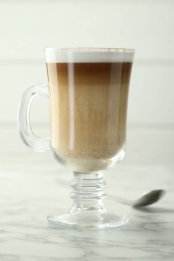 Cam bardakta latte macchiato, beyaz mermer masada, yakın plan.