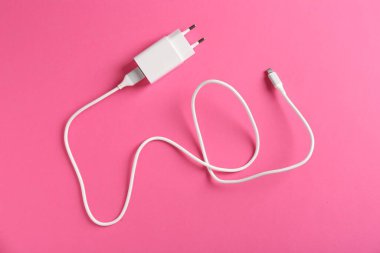 Pembe arka planda şarj kablosu olan USB güç adaptörü, üst görünüm