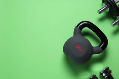Yeşil arka planda kettlebell ve dambıl, düz yatıyordu. Metin için boşluk