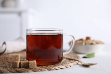 Fincanda koyu siyah çay ve beyaz masada kahverengi şeker küpleri, yakın plan.