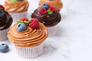 Çikolata kremalı ve beyaz mermer masaya böğürtlenli lezzetli kekler, yakın plan. Metin için boşluk