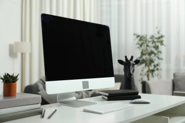 Beyaz masa üzerinde bilgisayar ve kırtasiye malzemesi olan modern işyeri.
