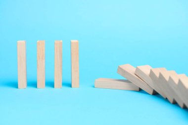 Domino etkisi. Açık mavi arkaplana düşen tahta bloklar