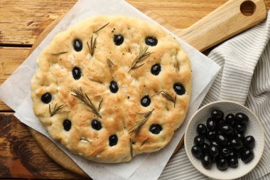 Lezzetli, zeytinli ve biberiyeli Focaccia ekmeği, ahşap masa, düz yatıyordu.