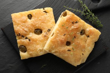 Zeytinli ve kekikli lezzetli Focaccia ekmekleri siyah masada, düz yatıyordu.