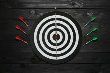 Dart tahtası ve siyah ahşap zemin üzerinde renkli oklar, düz yatıyordu.