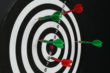 Siyah duvarda asılı renkli okları olan dart tahtası, yakın plan.