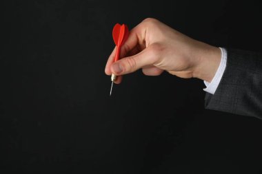 Siyah arka planda dart tutan adam, yakın plan. Metin için boşluk