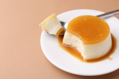 Açık kahverengi arka planda servis edilen karamel soslu lezzetli puding, yakın plan. Metin için boşluk