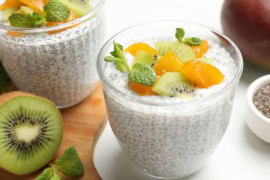 Kivili lezzetli chia pudingi, beyaz masada şeftali ve nane şekeri, yakın plan.