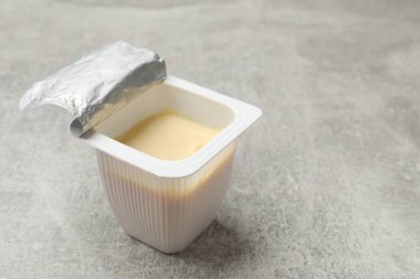 Gri desenli masada plastik bardakta lezzetli yoğurt, yakın plan. Metin için boşluk