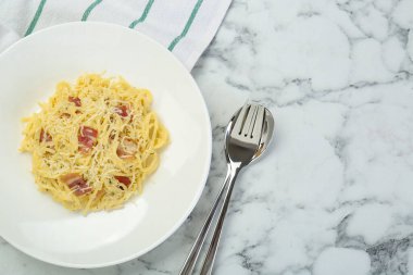 Beyaz mermer masada servis edilen domuz pastırmalı Carbonara makarnası. Metin için boşluk