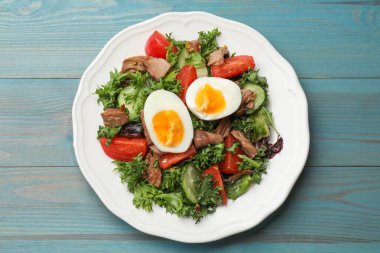 Açık mavi ahşap masada nefis taze ton balığı salatası.