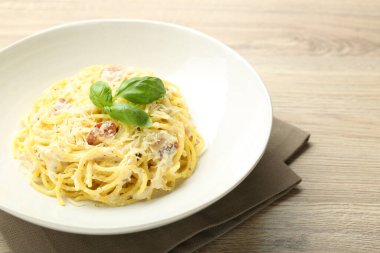 Tahta masadaki kasede Carbonara makarnası, yakın plan.