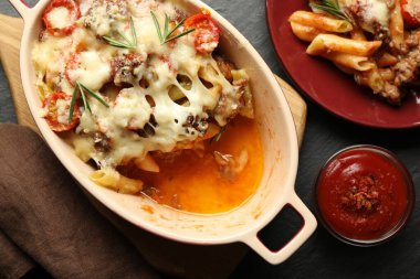 Düz kompozisyon ve koyu dokulu masa üzerinde lezzetli makarna güveci.