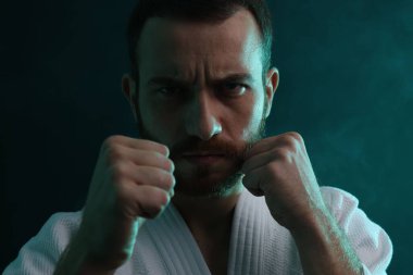 Karate dövüşçüsü üniforma giyiyor. Renkli ışıklar ve duman, yakın plan.