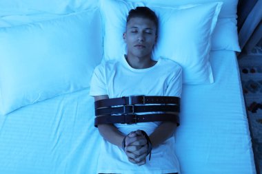 Uyurgezer kemerlerle bağlanır, yatağa uzanır.