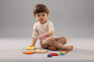 Gri arka planda oynayan sevimli küçük çocuk.