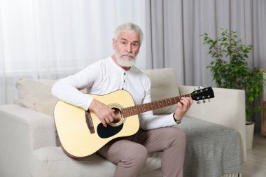 Rahatlatıcı hobi. Son sınıf öğrencisi evdeki kanepede gitar çalıyor.