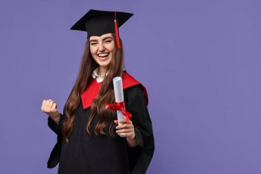 Mezuniyetten sonra mor arka planda diploması olan mutlu bir öğrenci. Metin için boşluk