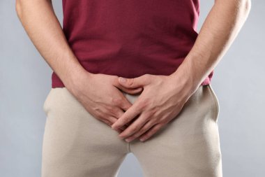 Cinsel yolla bulaşan hastalıklar. Gri arka planda semptomlardan muzdarip bir adam, yakın plan