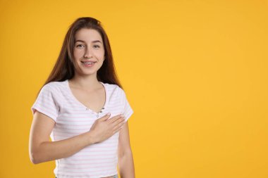 Kadın turuncu arka planda söz veriyor, mesaj için yer var. Yemin jesti