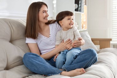 Mutlu anne ve tatlı küçük oğlu evdeki kanepede.
