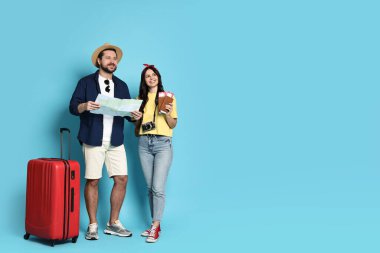 Turizm. Açık mavi arkaplanda haritası ve bavulu olan mutlu çift, metin için boşluk