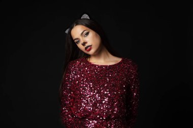 Kedi makyajı ve siyah arka planda kulakları olan çekici bir kadın.