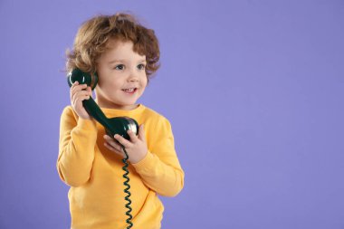 Menekşe arka planında telefon ahizesi olan şirin küçük çocuk, mesaj için yer var.