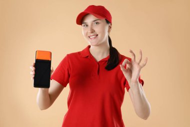 Ödeme terminali olan mutlu kurye bej arka planda iyi bir hareket gösteriyor