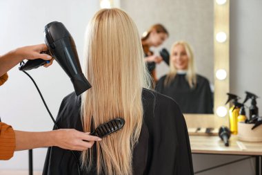 Kuaför kuaför kuaförde müşterinin saçını kurutuyor.