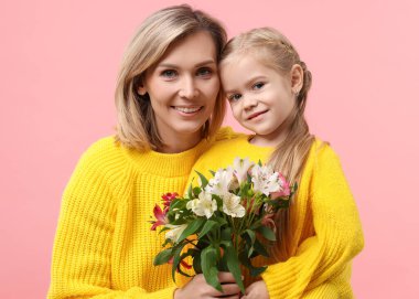 Happy woman with her daughter and bouquet of alstroemeria flowers on pink background. Mother's Day celebration clipart