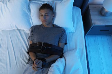 Uyurgezer kemerlerle bağlanır, yatağa uzanır.