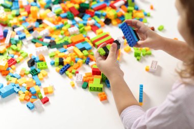 Beyaz masadaki yapı taşlarıyla oynayan kız, yakın plan.
